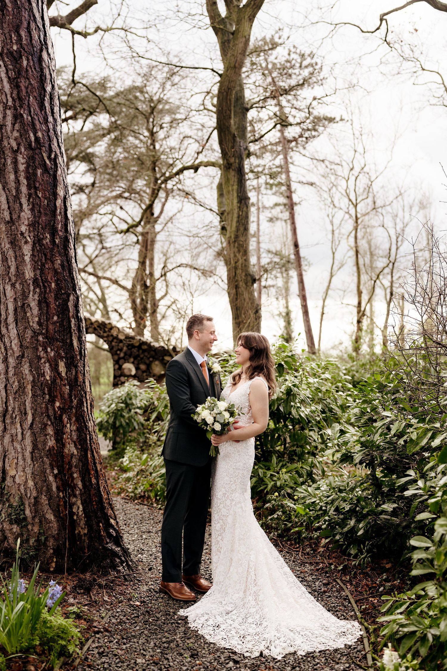 Bride and groom sharing a romantic moment in a woodland garden setting on their wedding day.