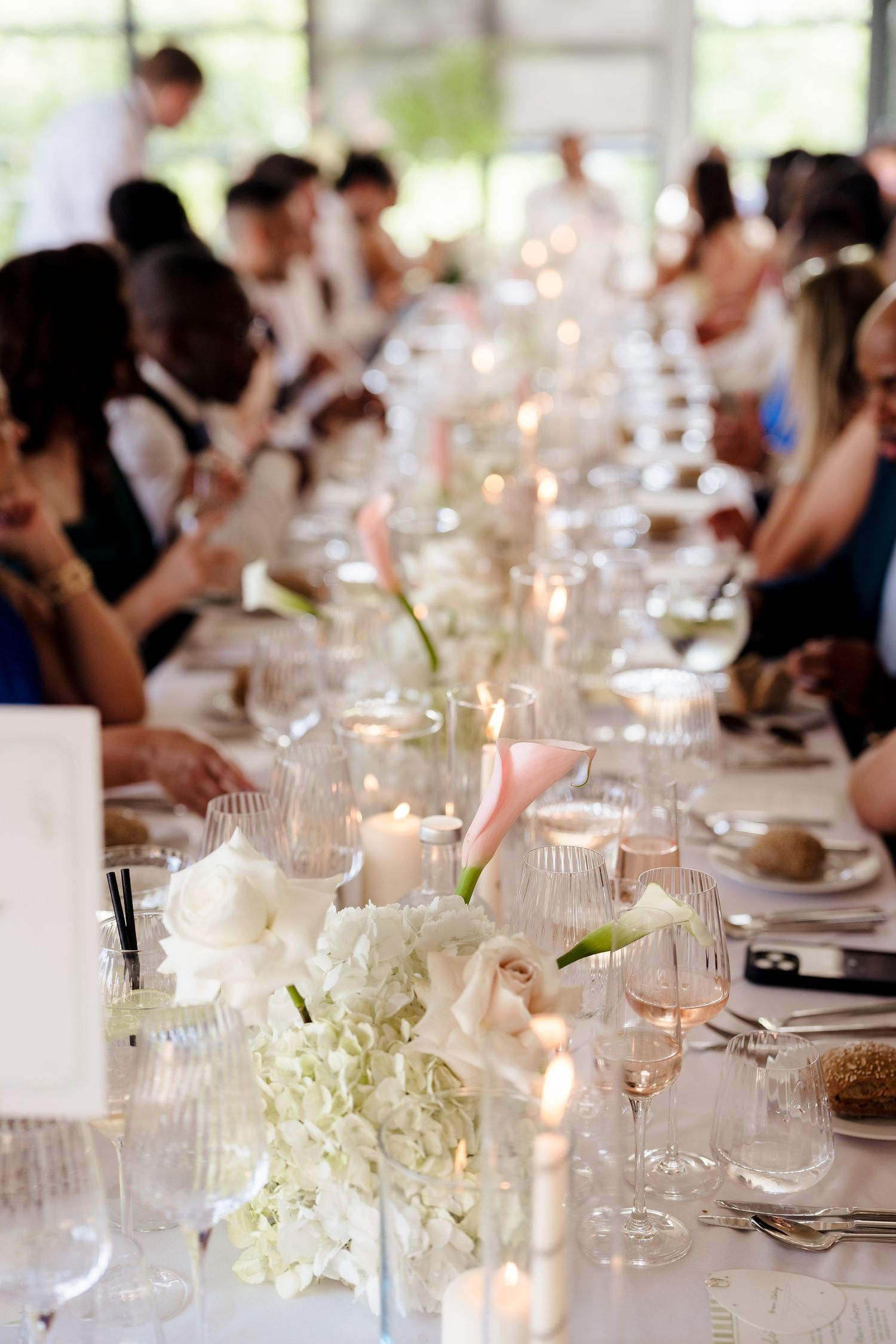 Elegant wedding reception table with white hydrangeas, pink calla lilies, and candles.