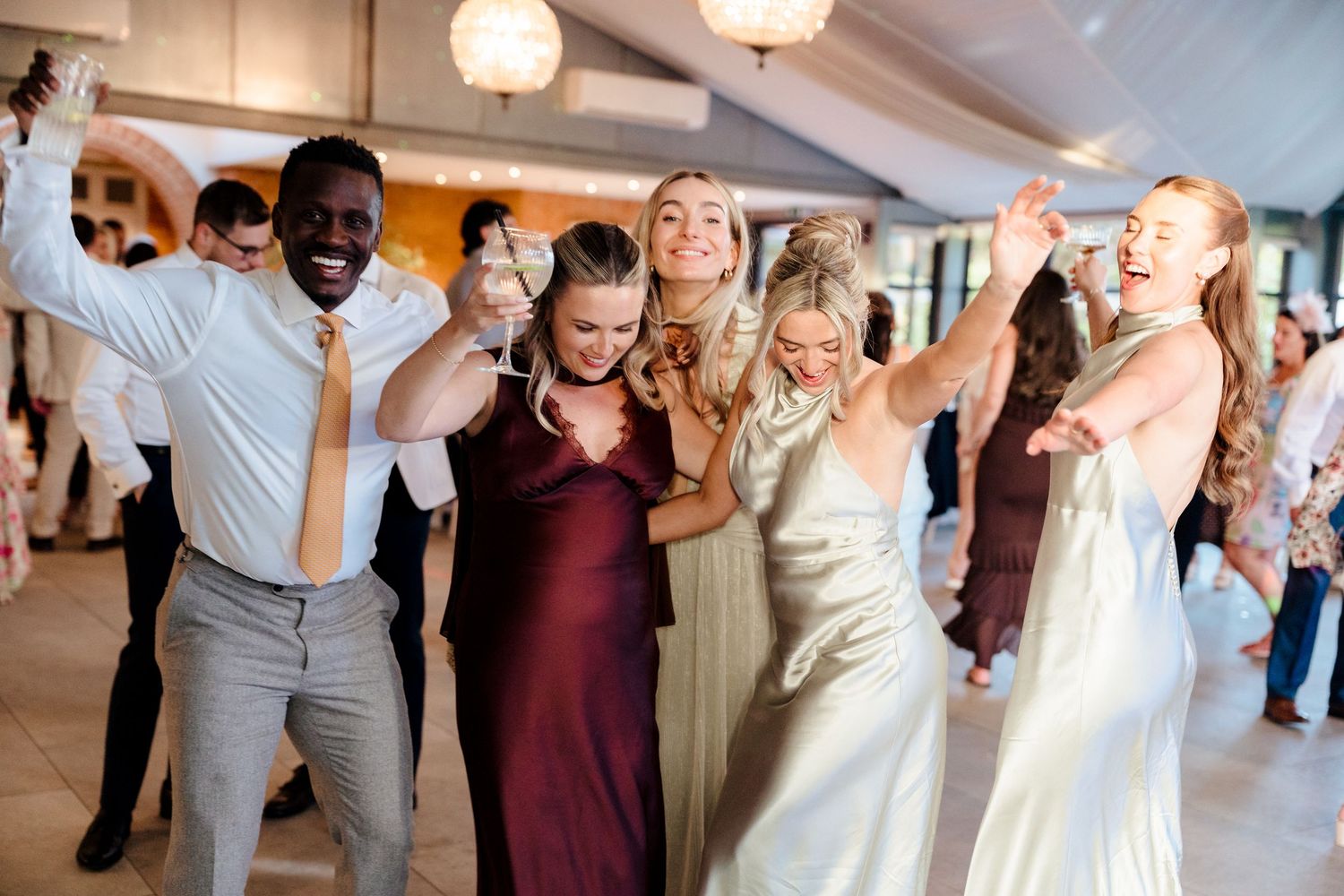 Joyful wedding guests dancing and celebrating on the dance floor during lively reception party.
