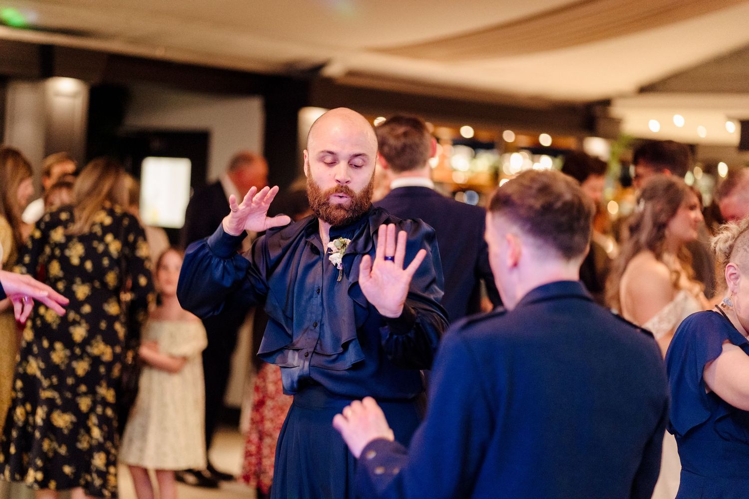 Bald bearded wedding guest dancing energetically on the dance floor at a wedding reception.