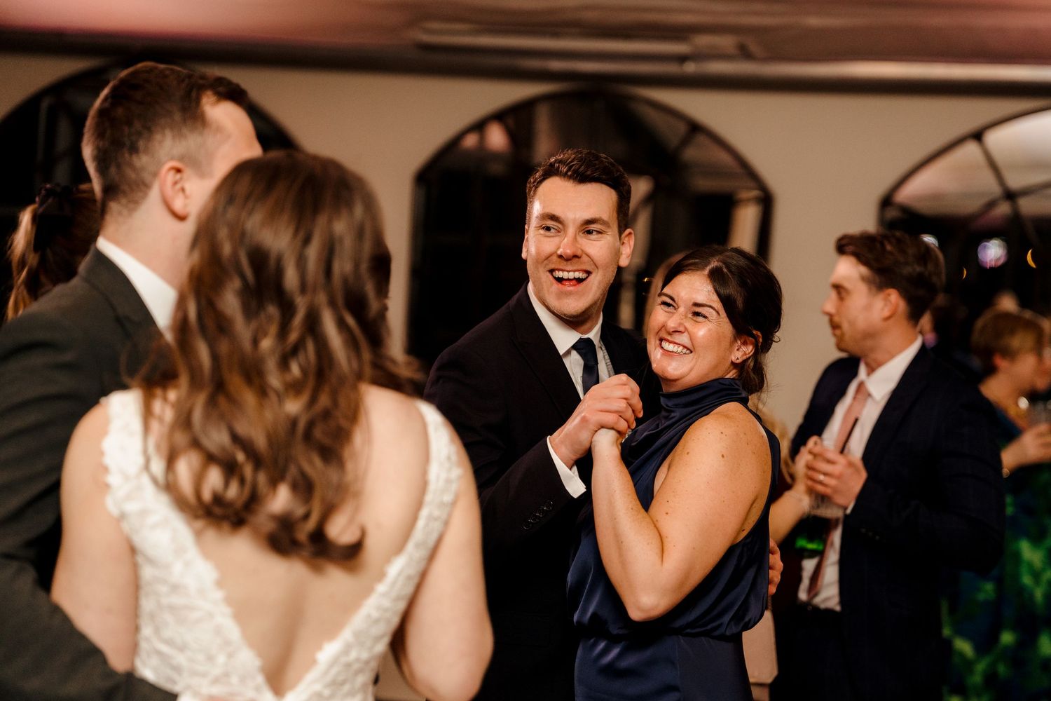 Guests laughing and dancing at lively wedding reception on the dance floor.