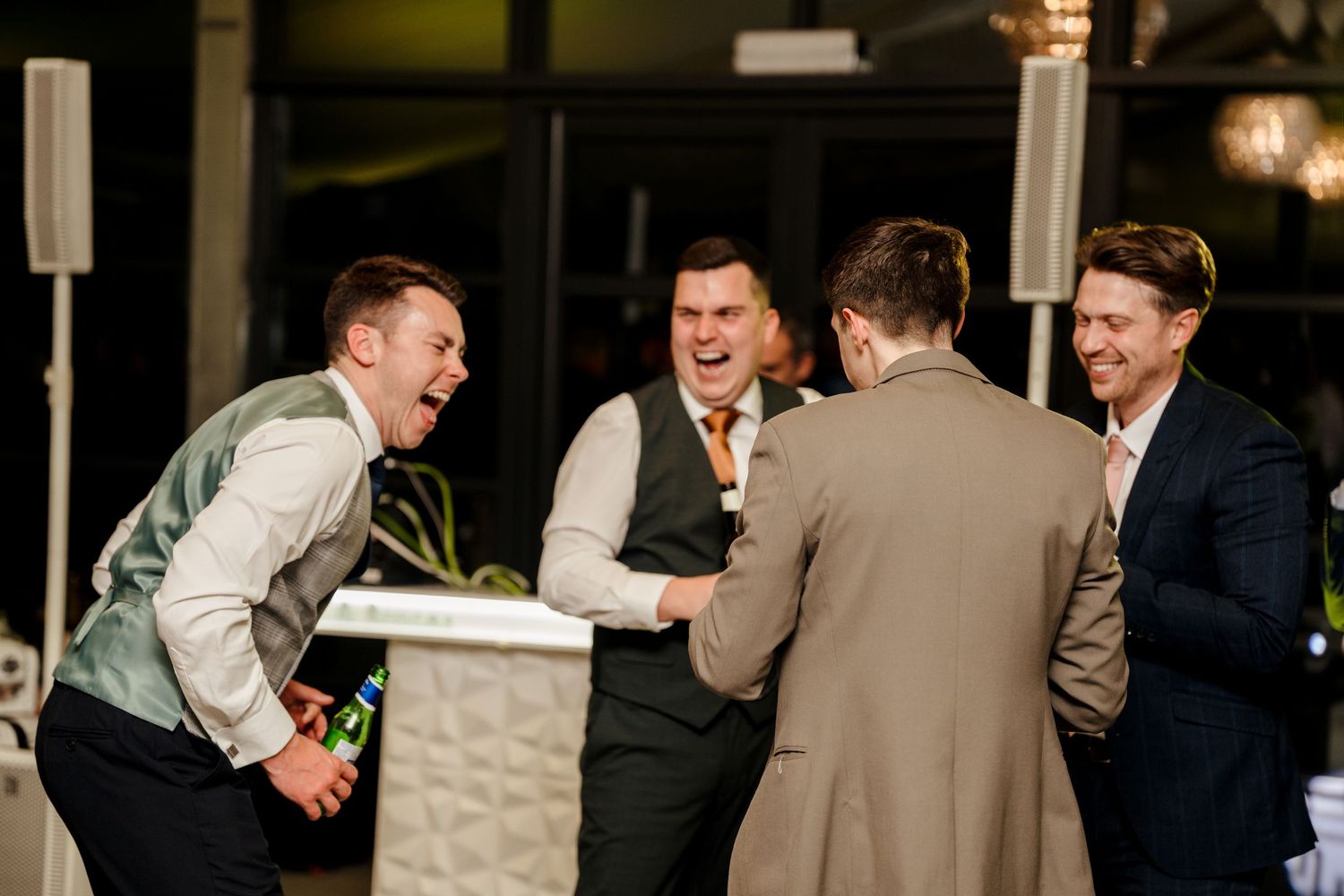 Group of groomsmen laughing together at wedding reception celebration.