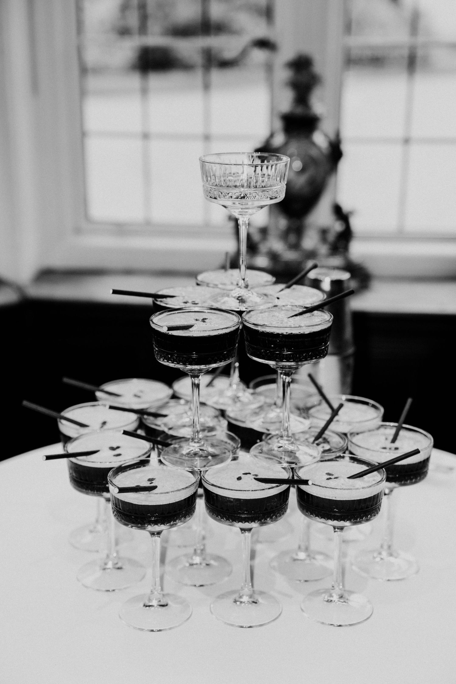 Black and white pyramid of espresso martini cocktails displayed on white tablecloth.