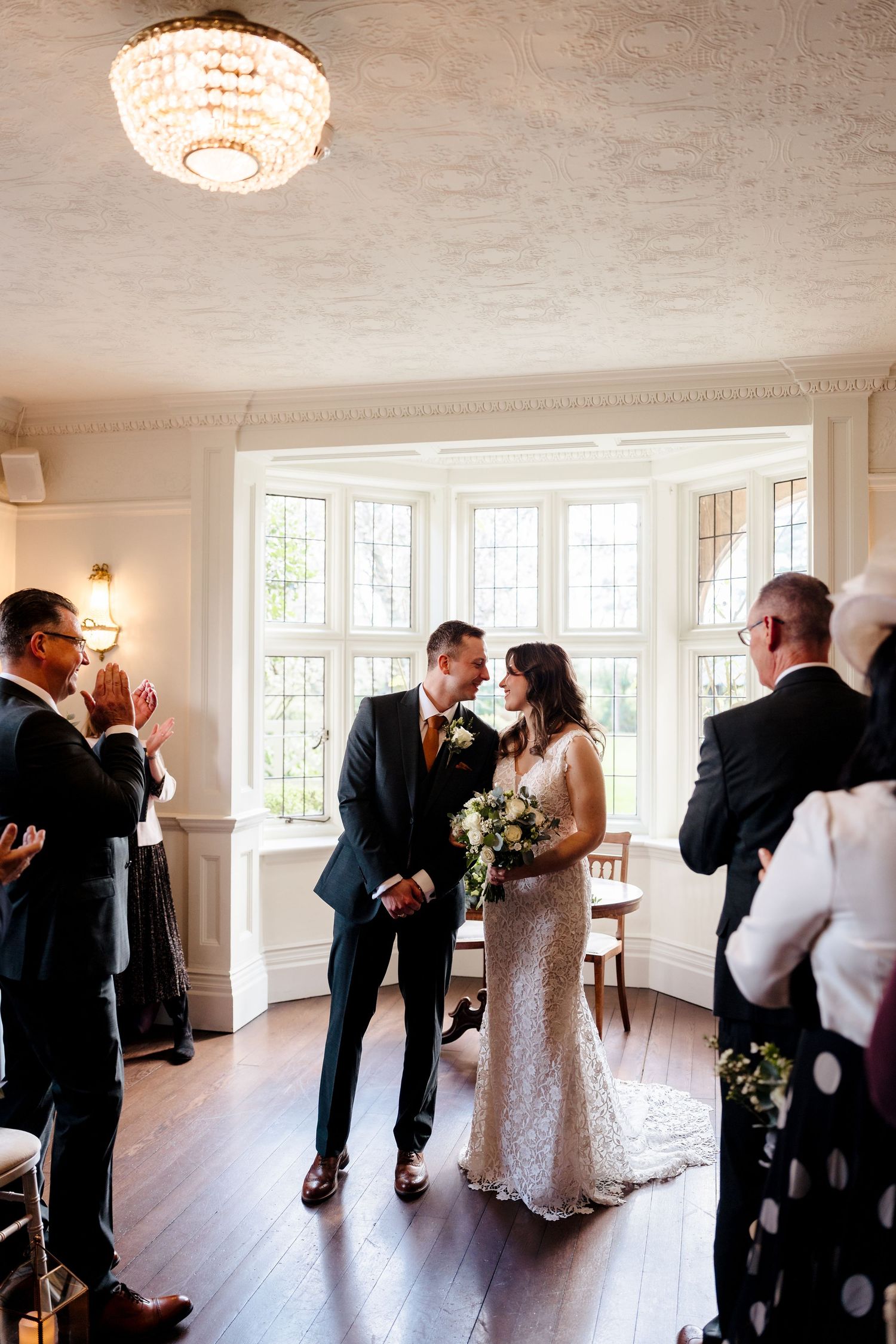 Newlyweds share an intimate moment at the altar as guests applaud their union.