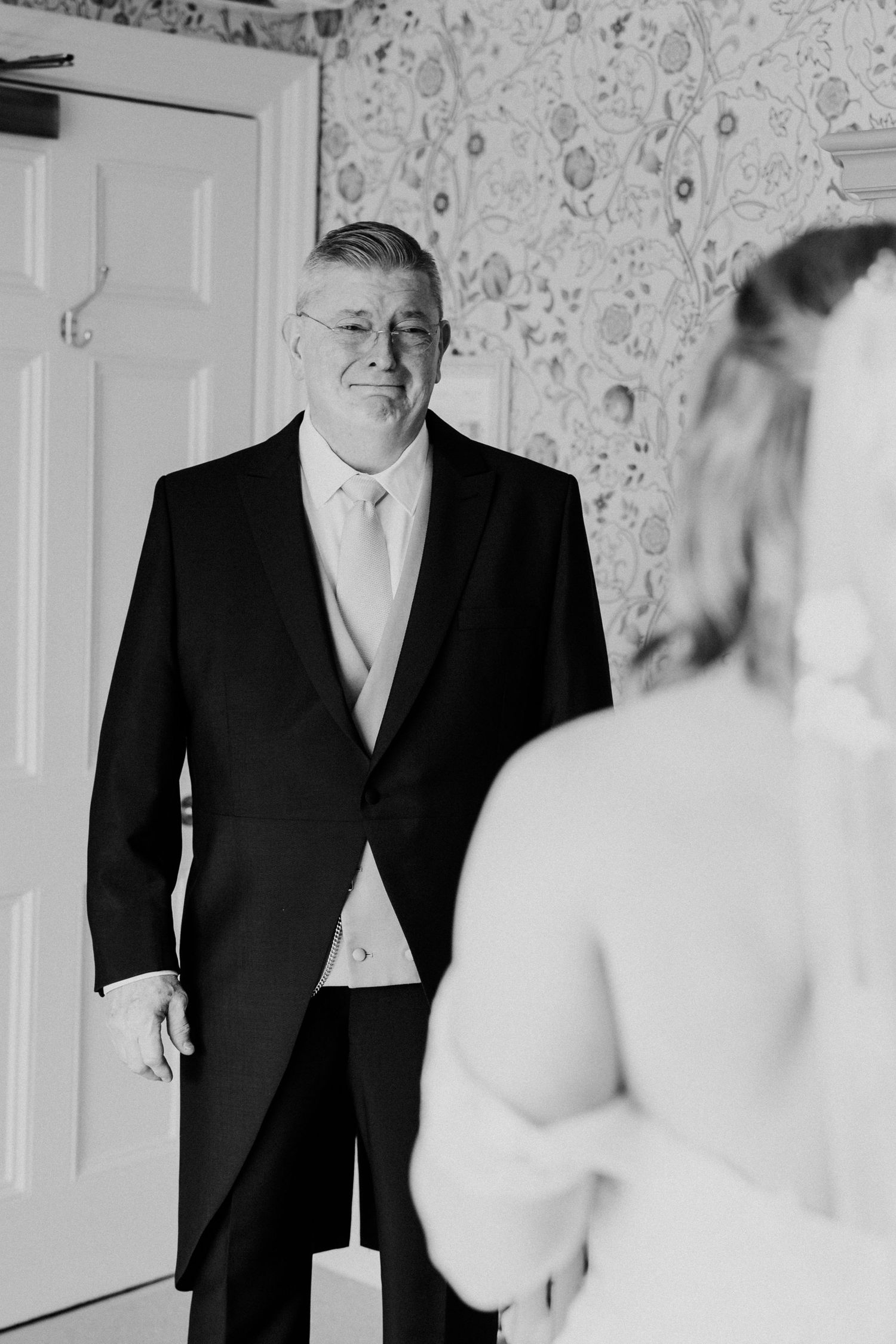 Emotional father seeing bride for first time in black and white first look moment.
