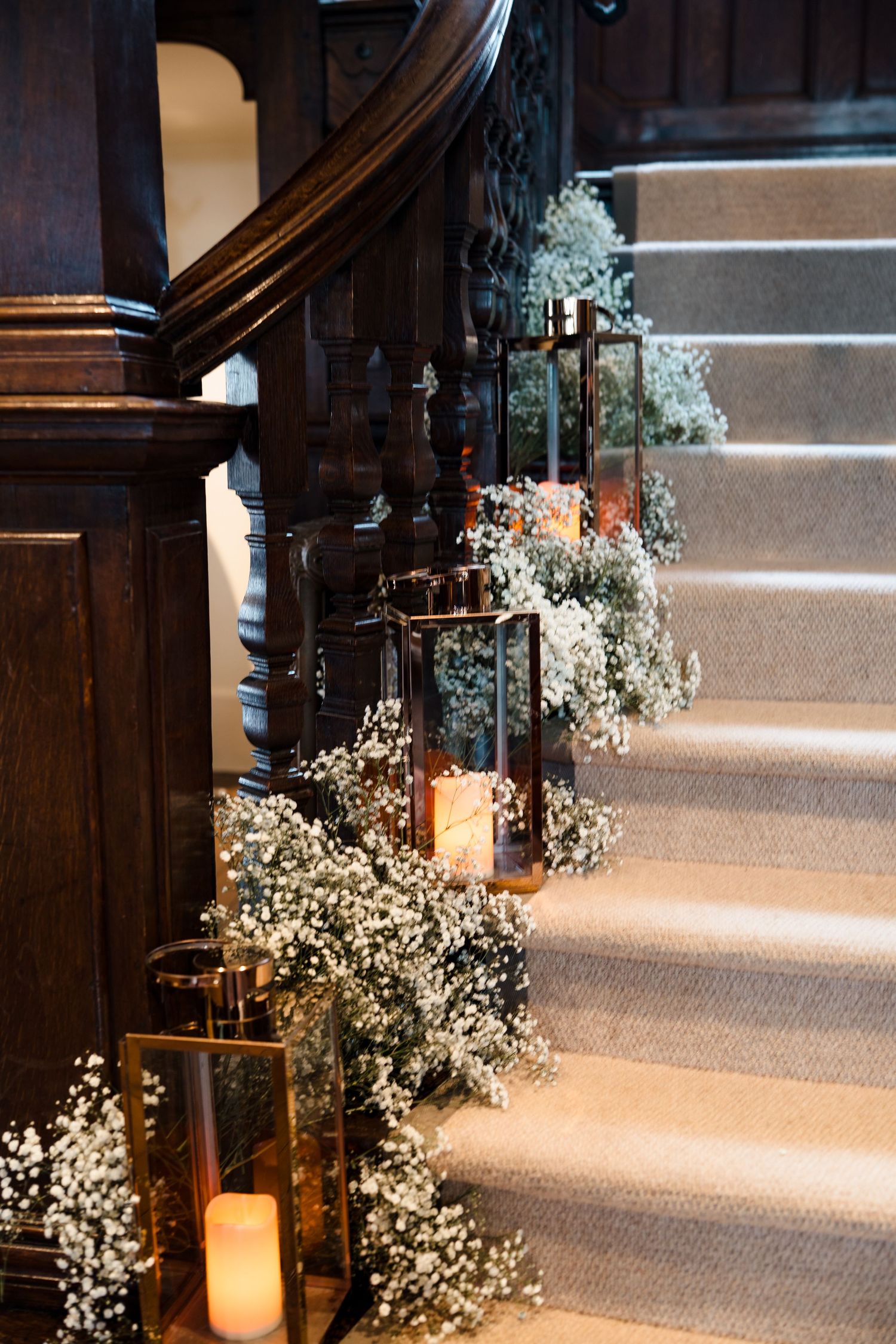 Elegant staircase decorated with baby's breath flowers and glowing lantern candles for a wedding.