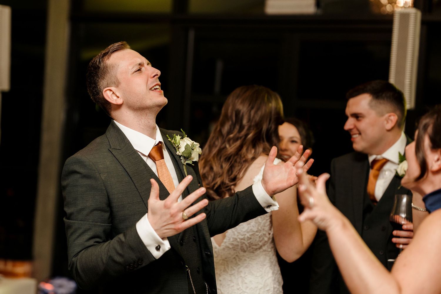Groom reacts with joy and laughter on the dance floor surrounded by wedding guests.