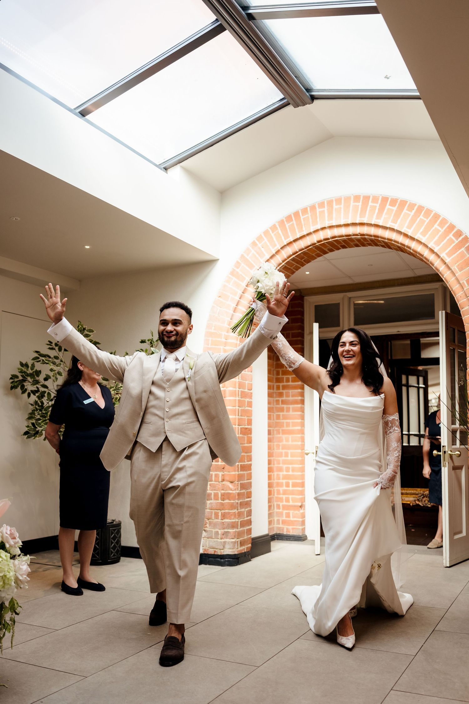 Bride and groom celebrating their grand entrance through a brick archway at their wedding.