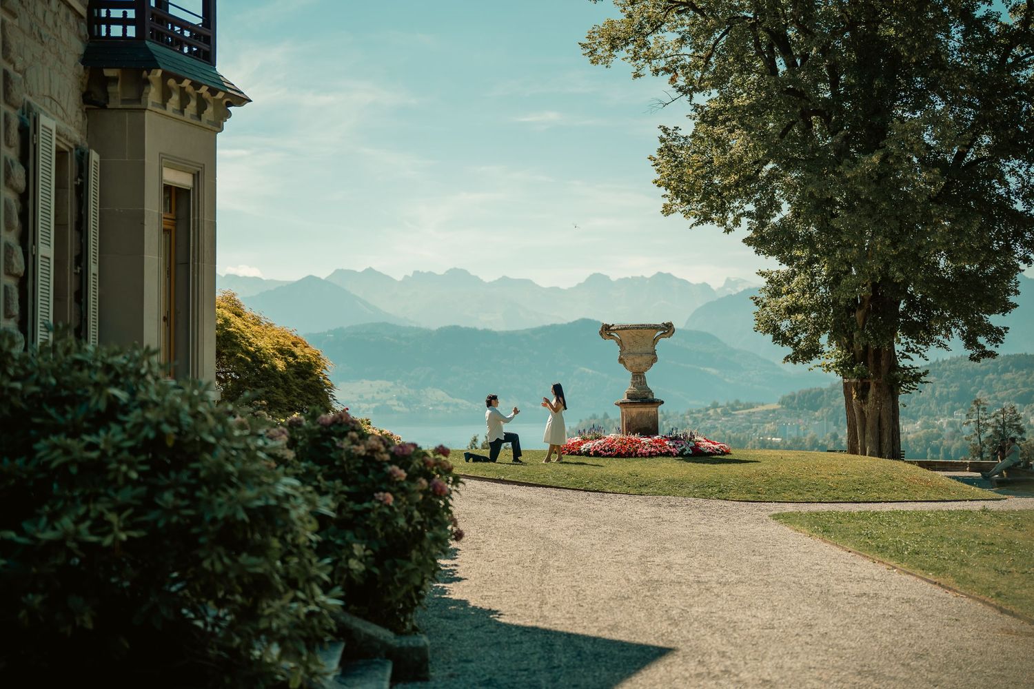 Romantic marriage proposal at a luxury villa terrace with stunning Alpine mountain views and manicured gardens.