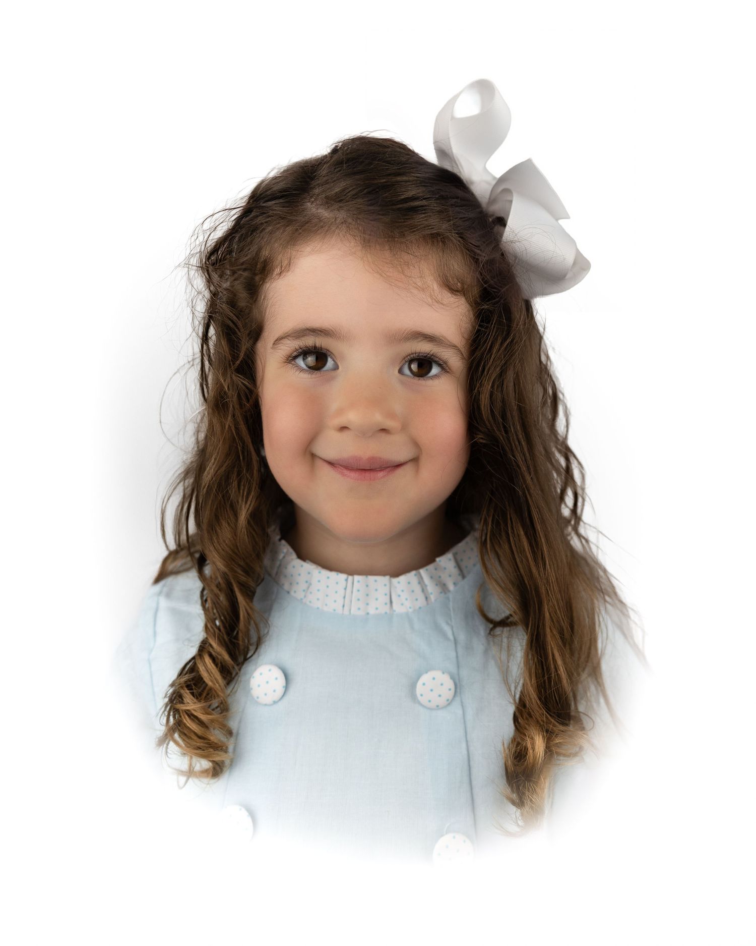 Young girl with long brown hair in a light blue dress with white buttons and bow accessory.