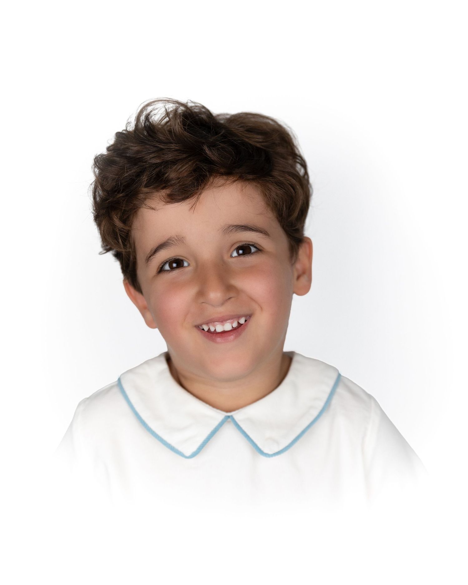 Smiling young boy with curly brown hair wearing a white shirt with blue trim collar.