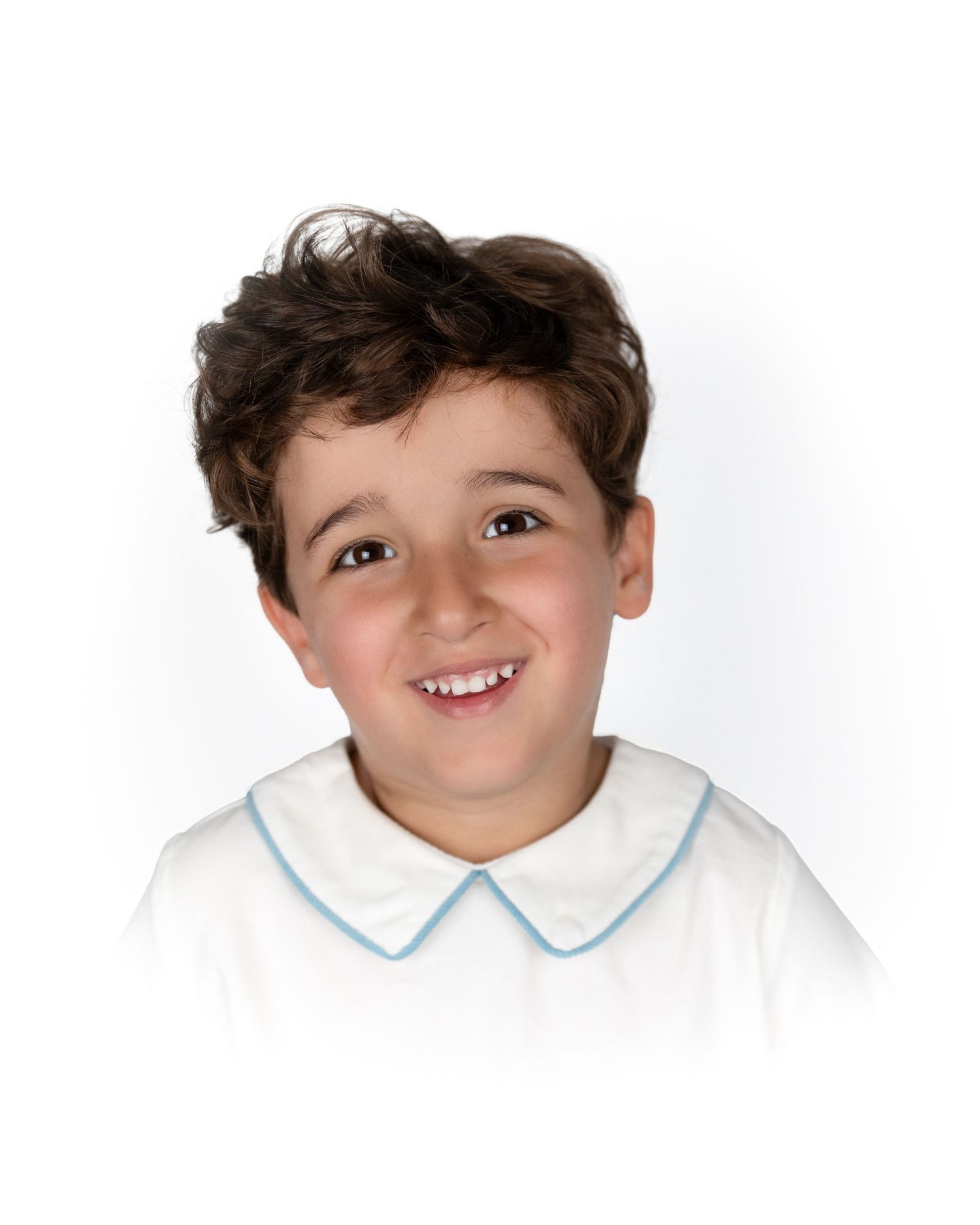 Smiling young boy with curly brown hair wearing a white shirt with blue trim collar.