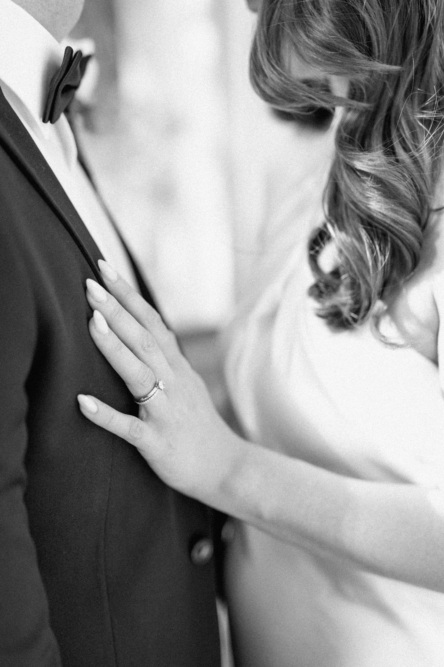 Black and white close-up of Brooke’s hand resting on Lloyd’s suit