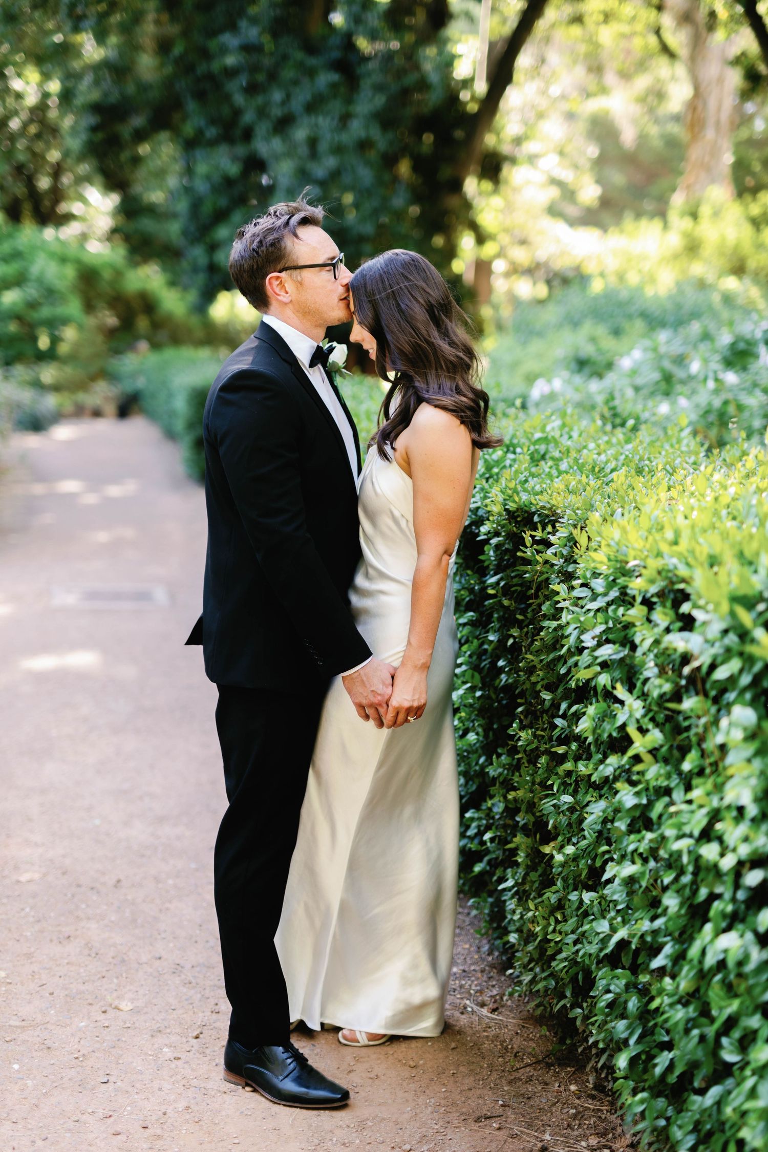 Brooke and Lloyd standing together on a sunlit path at Adelaide Botanic Garden.
