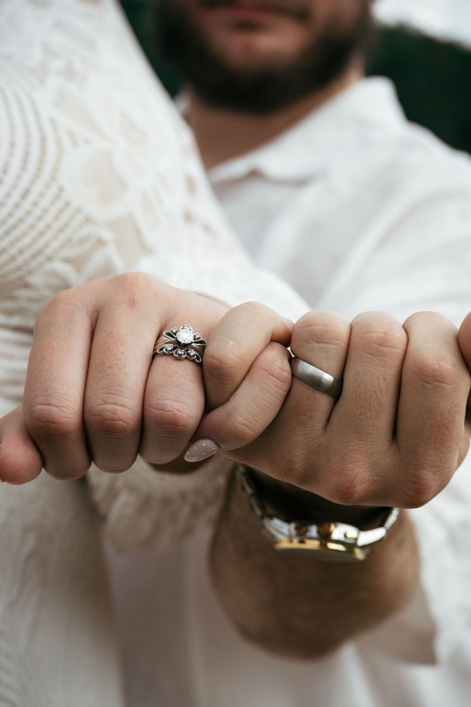 Newlyweds showing wedding rings, bride wearing ornate diamond ring and groom wearing simple silver band.