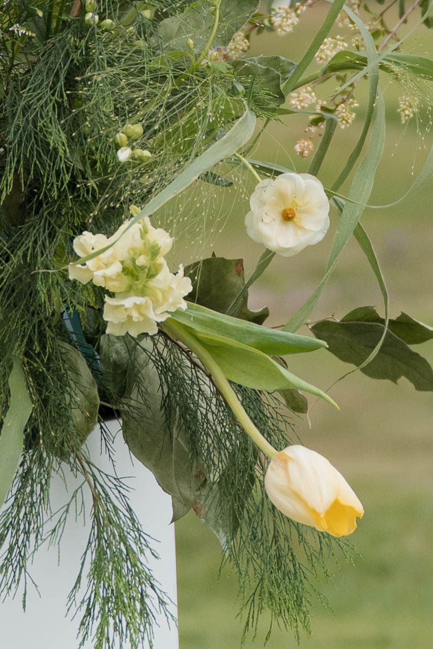 Delicate white tulip and anemone wedding floral arrangement with greenery and ferns.