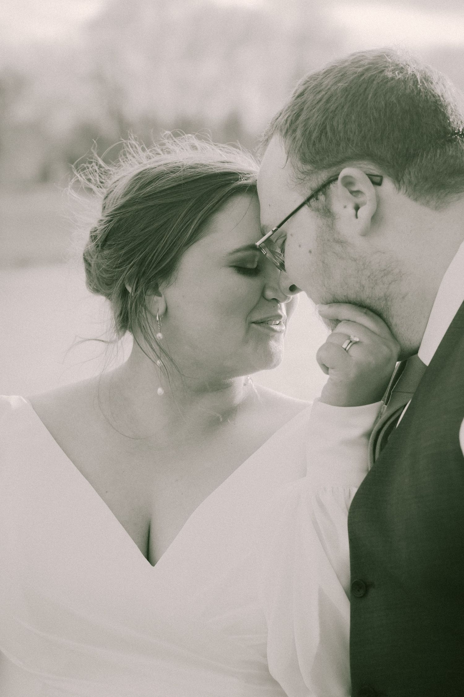 Black and white portrait of bride and groom sharing an intimate forehead kiss on their wedding day.