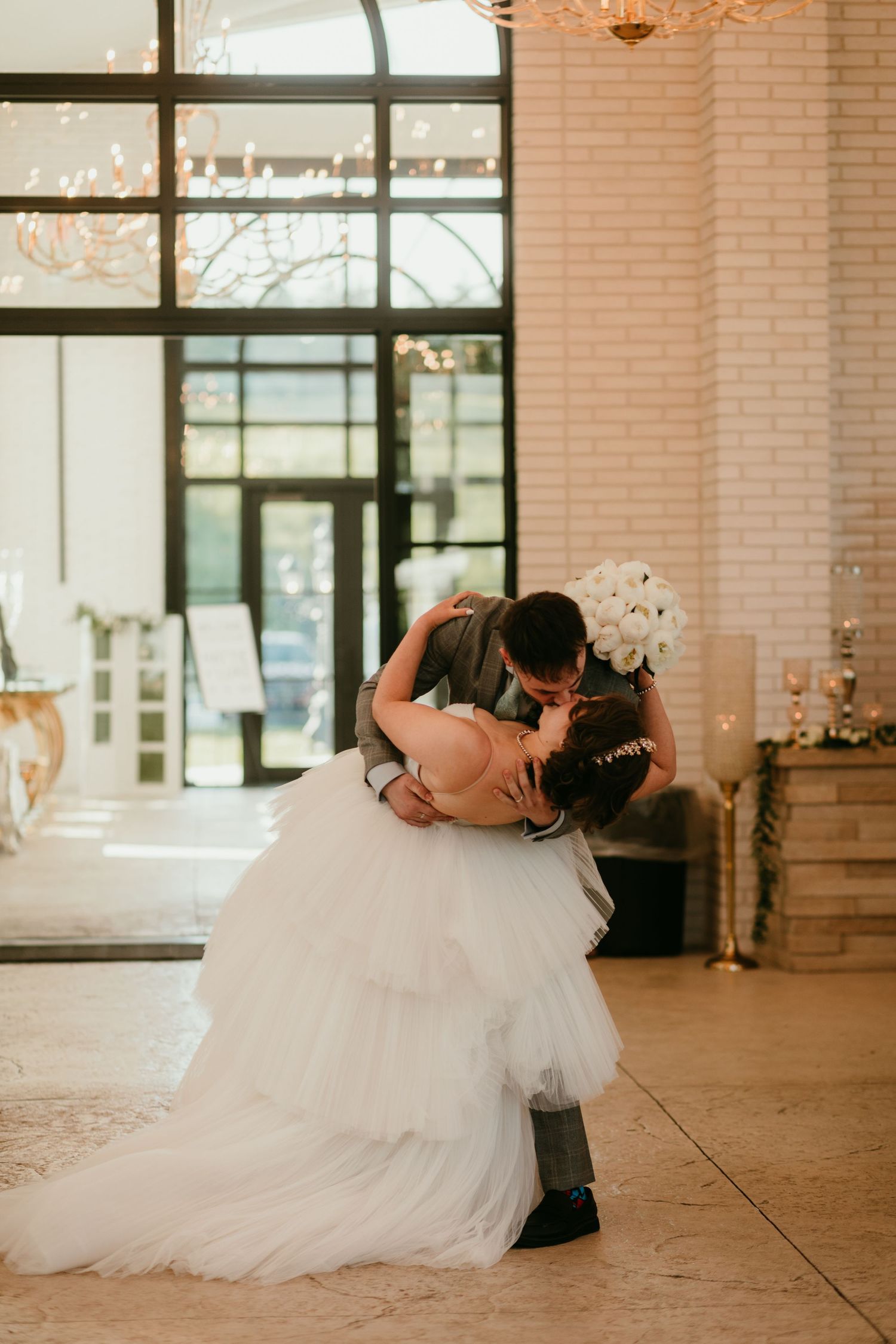 Bride and groom share a romantic dip kiss during their first dance at an elegant wedding reception.