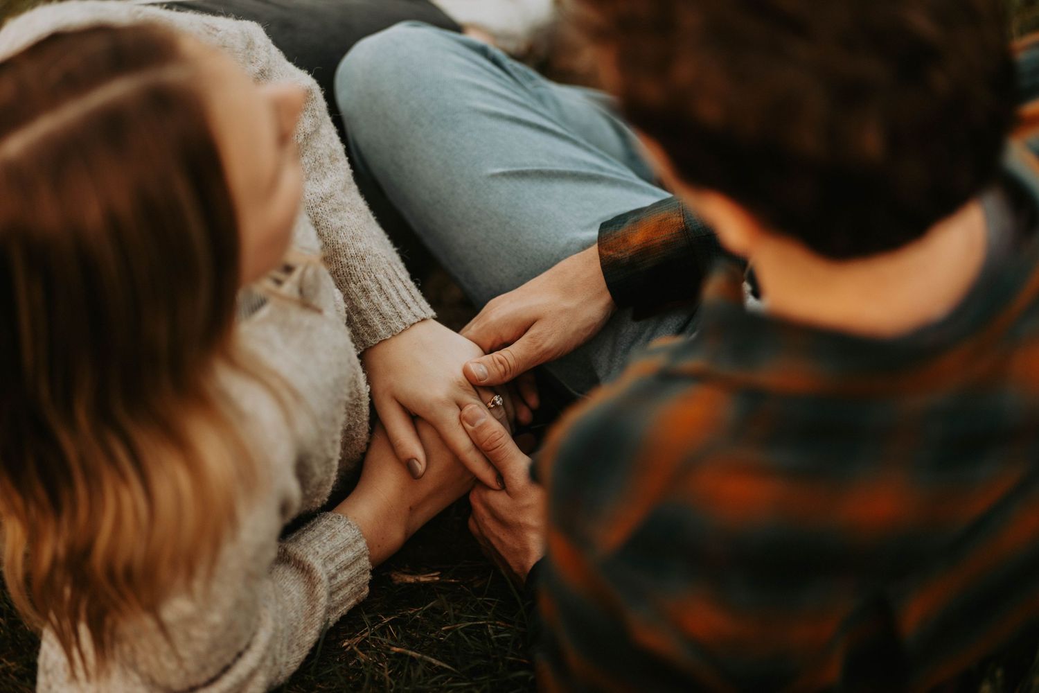 Couple holding hands while sitting together outdoors in a cozy casual setting.