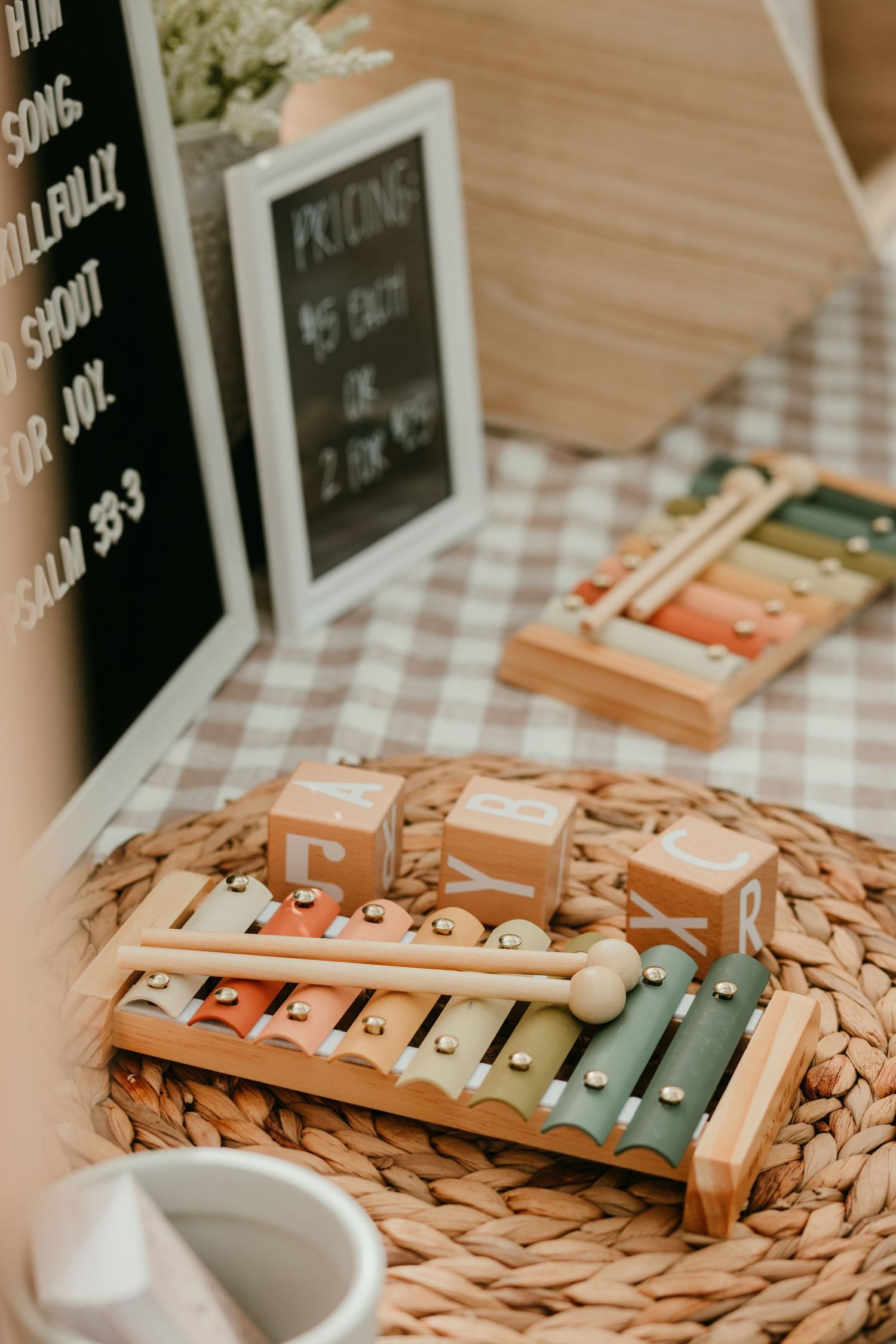 Wooden xylophone toy and alphabet blocks arranged on a woven mat at a baby shower display.
