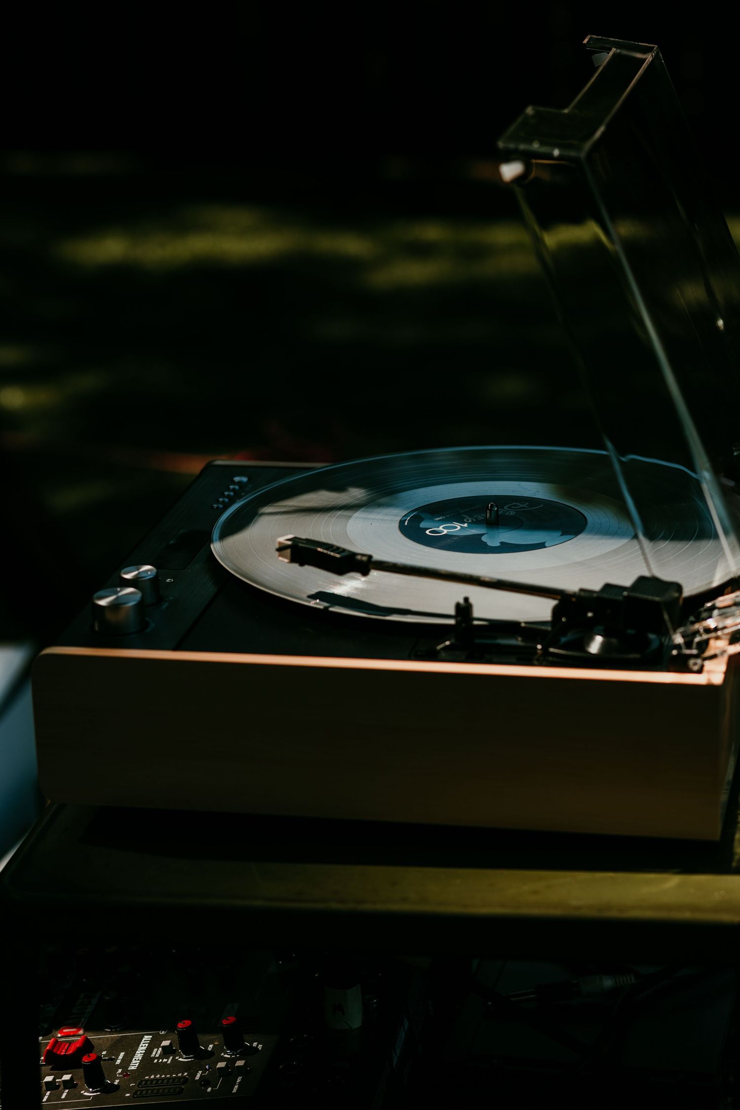 Vintage vinyl record player spinning at an outdoor wedding reception in soft natural light.