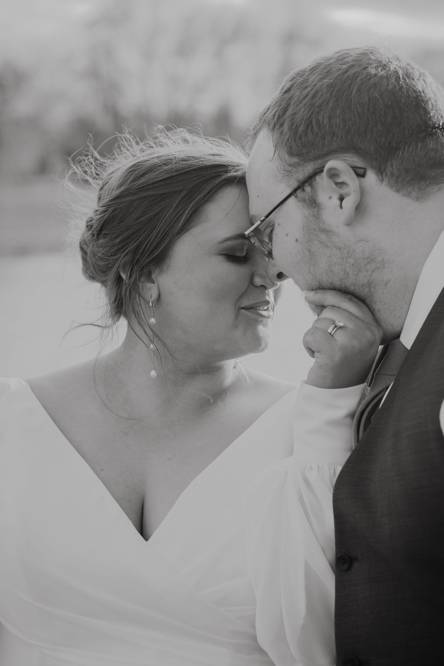 Elegant black and white close-up of bride and groom sharing a tender forehead kiss at their wedding.