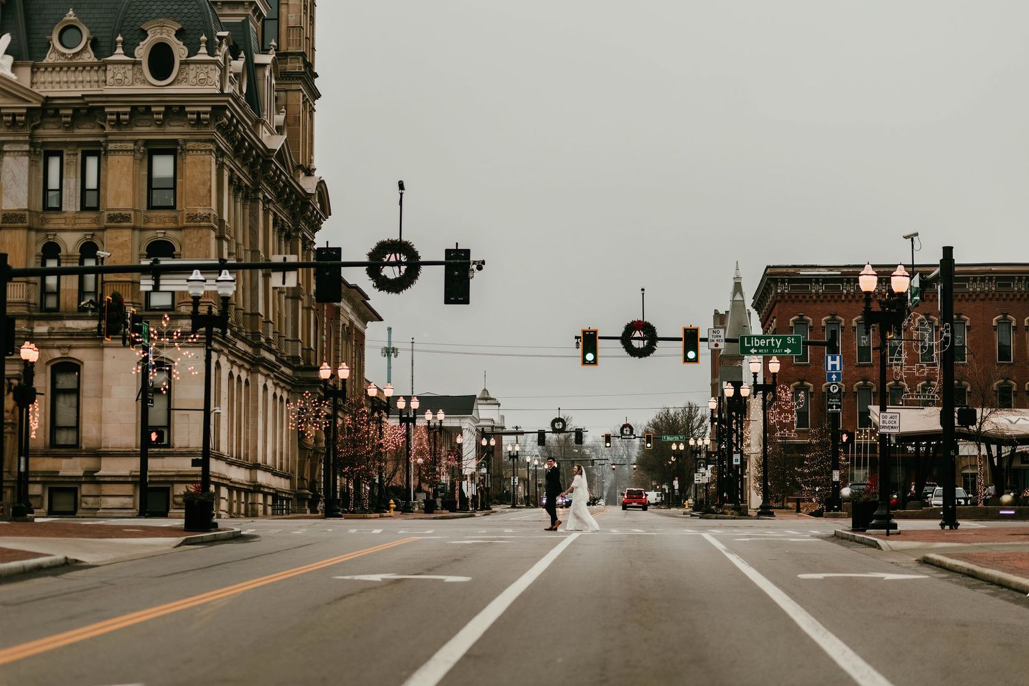 Bride and groom kissing in the middle of an empty downtown city street intersection.