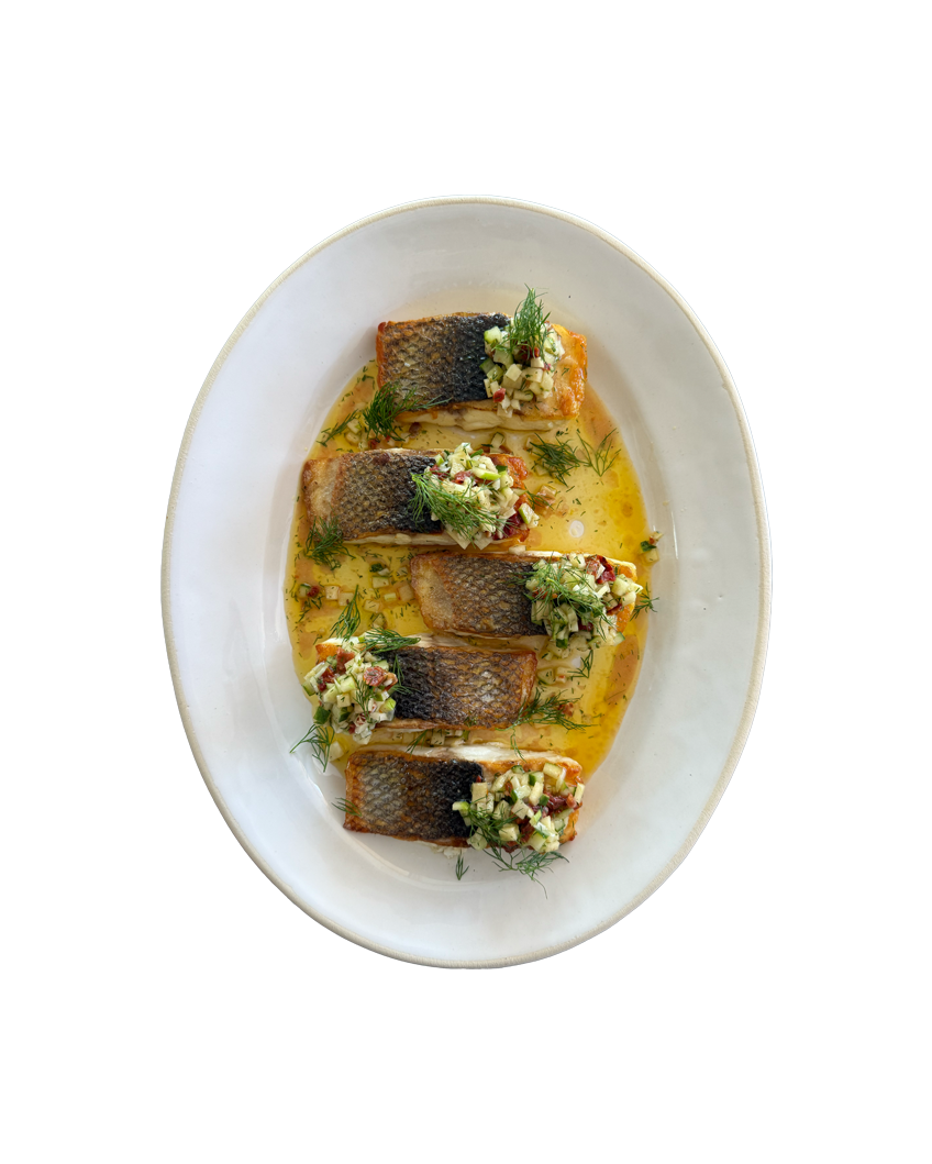 Pan-seared fish fillets in golden butter sauce topped with fresh herb salsa verde on a white oval ceramic plate.