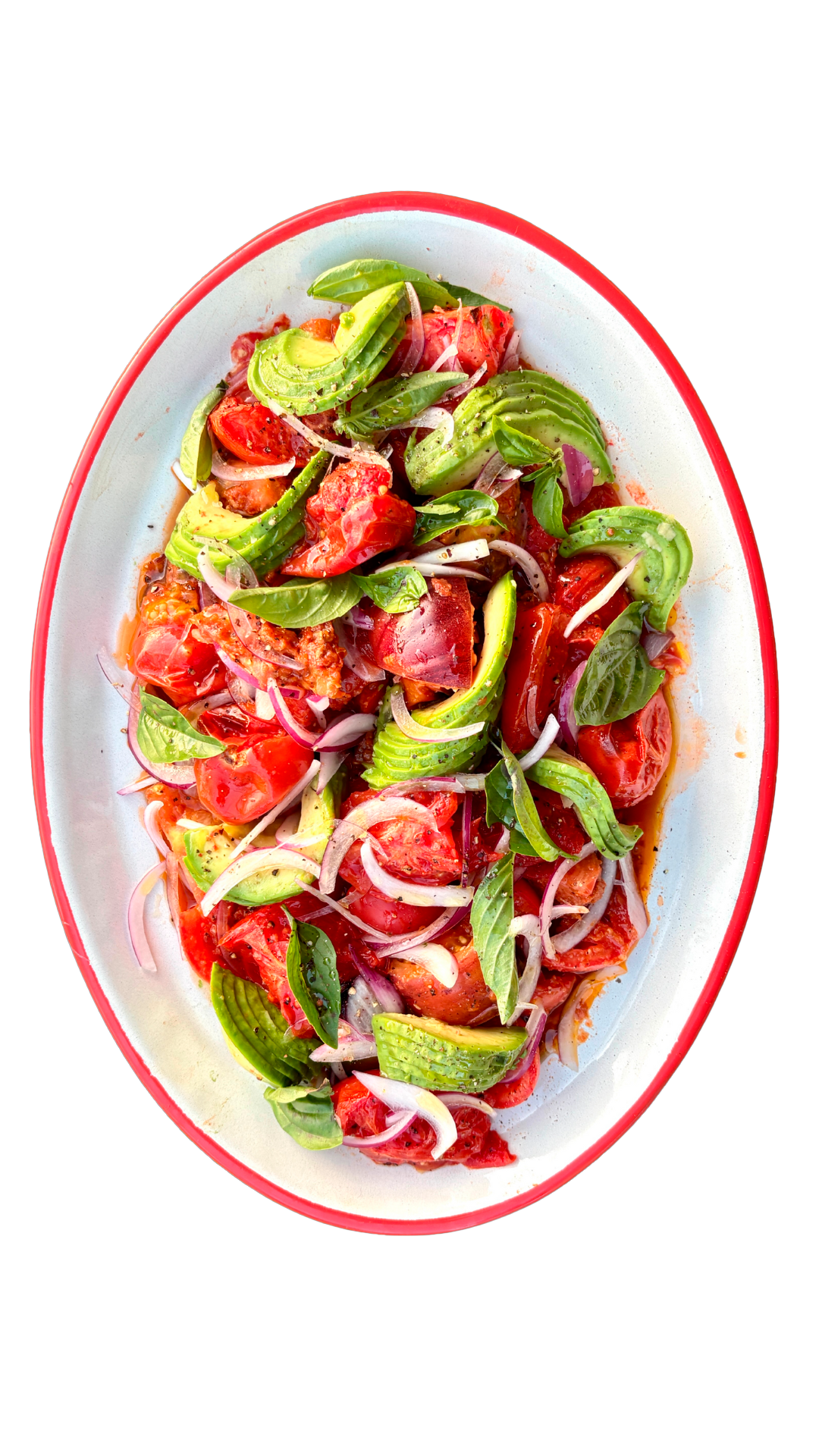 Fresh tomato and avocado salad with red onion and basil leaves in vinaigrette on a red-rimmed white oval platter.