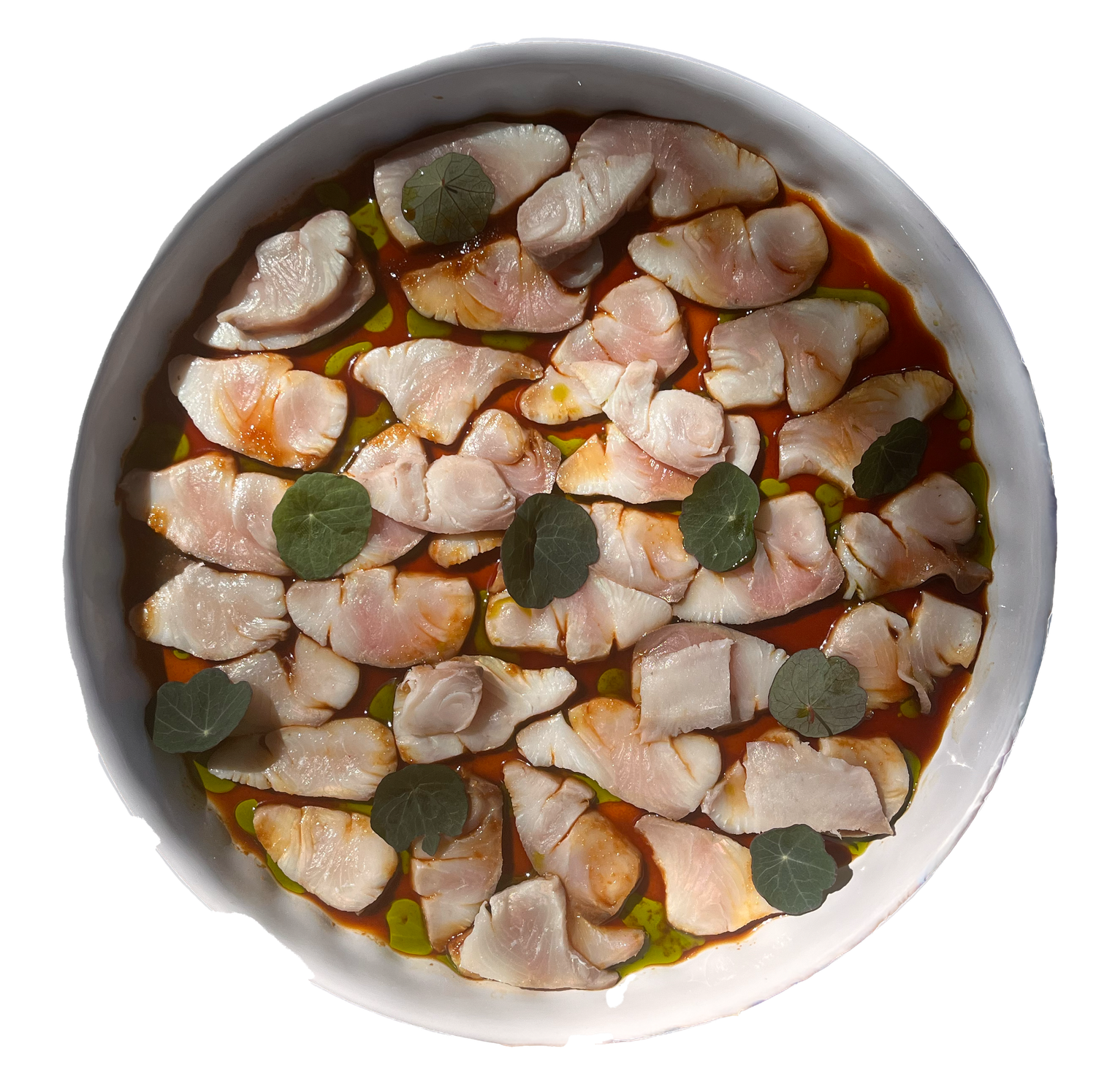Fresh fish ceviche with sliced raw fish in citrus marinade, garnished with green herb leaves in a white bowl.