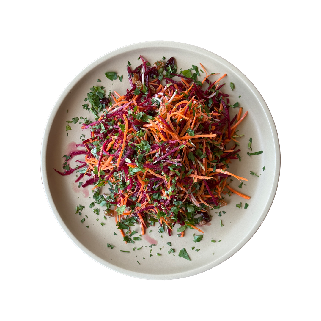 Colorful coleslaw with shredded red cabbage, carrots, and fresh herbs served on a white ceramic plate.