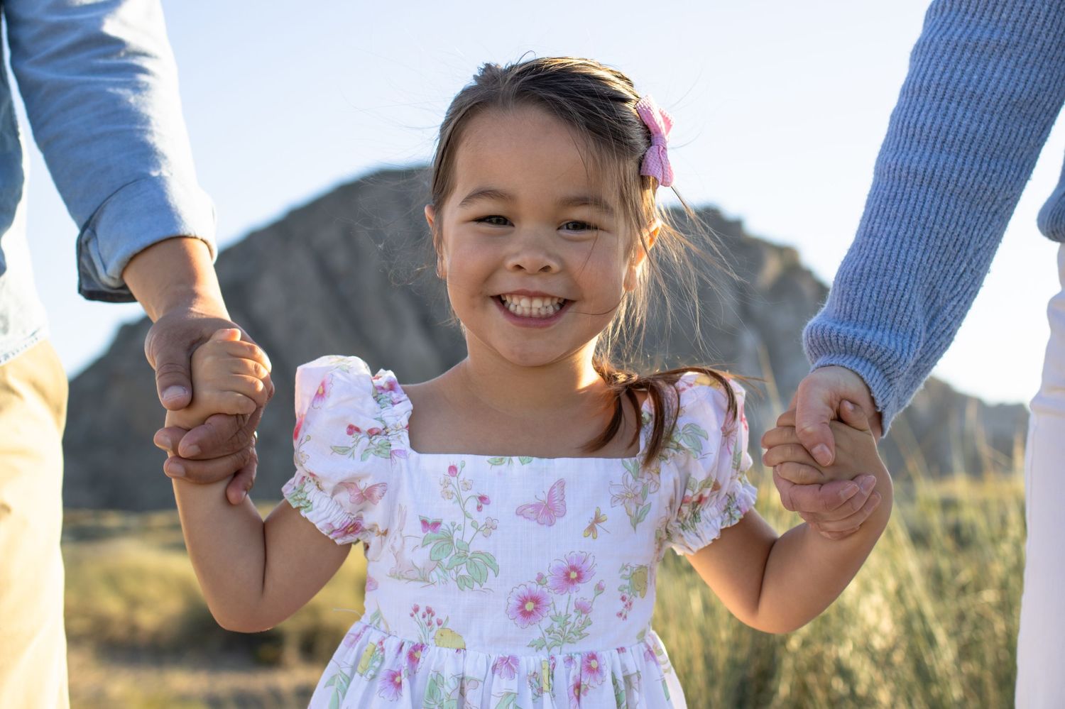 Little girl holding parents hands, candid family photography Central Coast