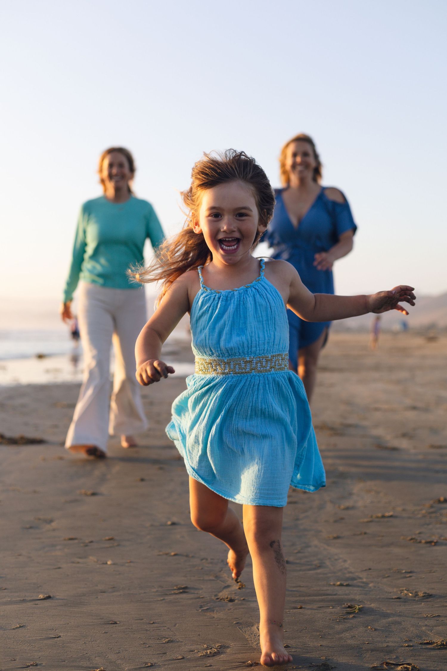 Family running and playing together during a joyful beach family photography session on the Central Coast of California.