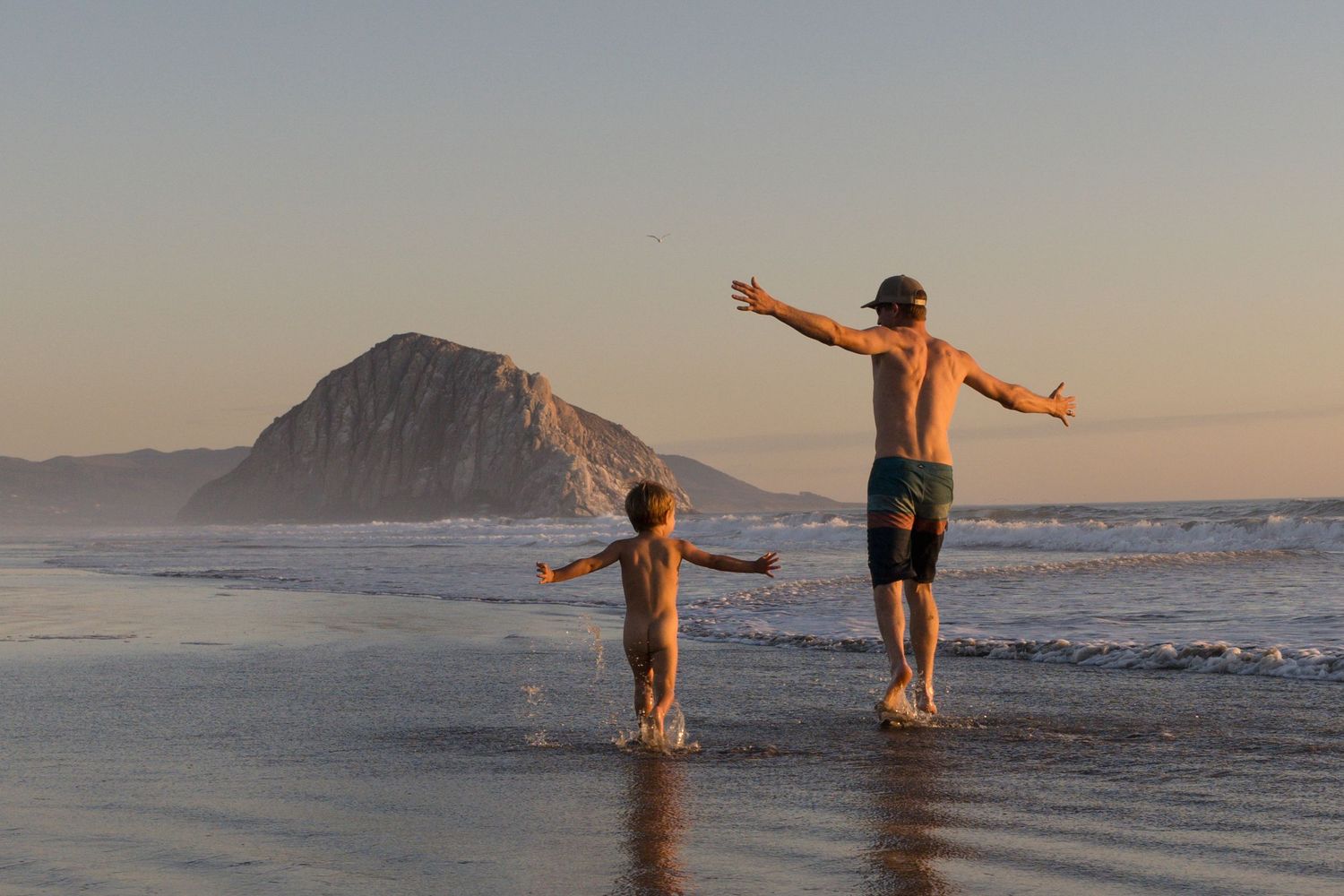 Family playing together on the beach with Morro Rock in Morro Bay, California