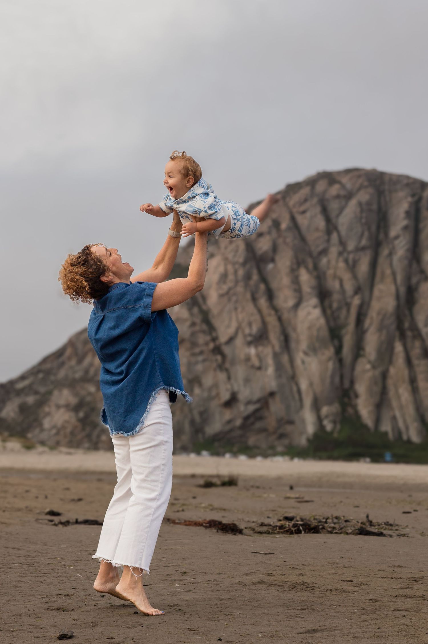 Father lifting his baby during a playful family photography session at the beach in Morro Bay, California.
