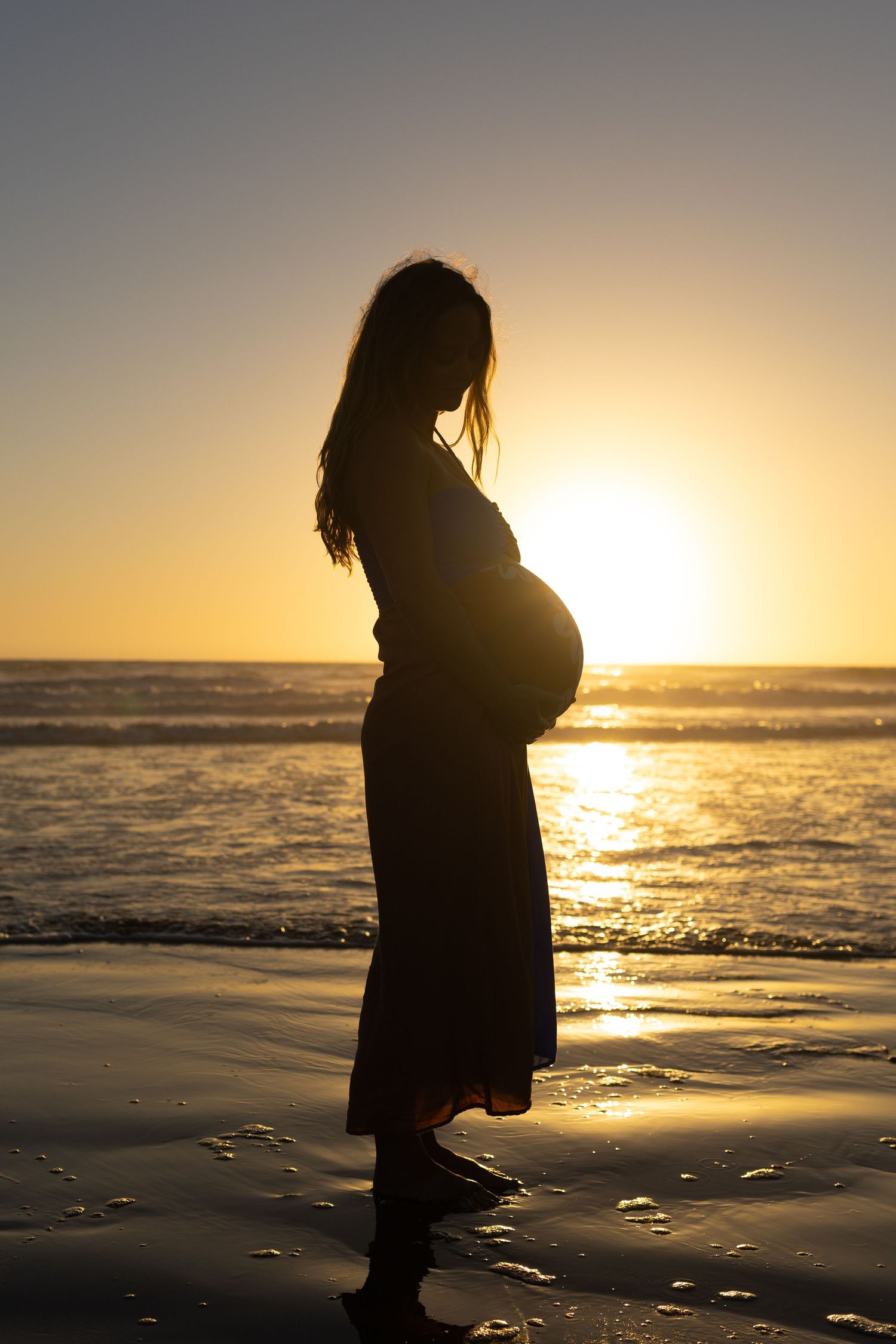 Pregnant mother enjoying a beach sunset during a maternity session in cayucos, California
