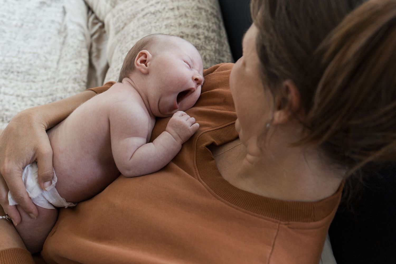 Mother cuddling her newborn baby during a lifestyle newborn session