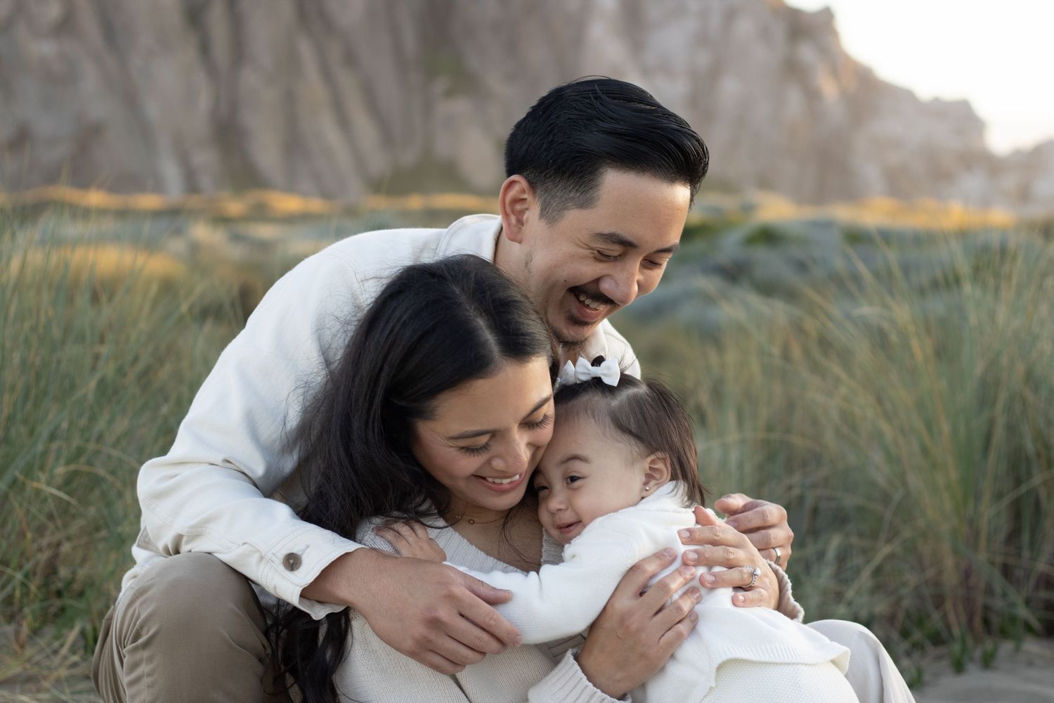 Parents cuddling their baby during a natural family photography session on the Central Coast of California.