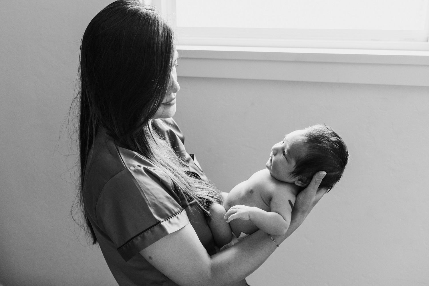 Lifestyle newborn photography of a mother holding her baby at home