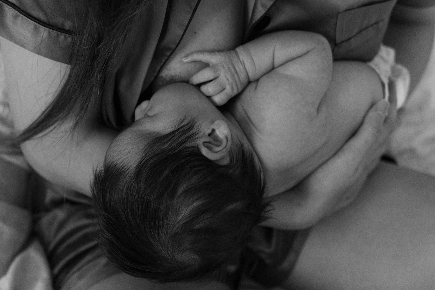 Mother gently cuddling her newborn baby during an intimate lifestyle newborn photography session in California.