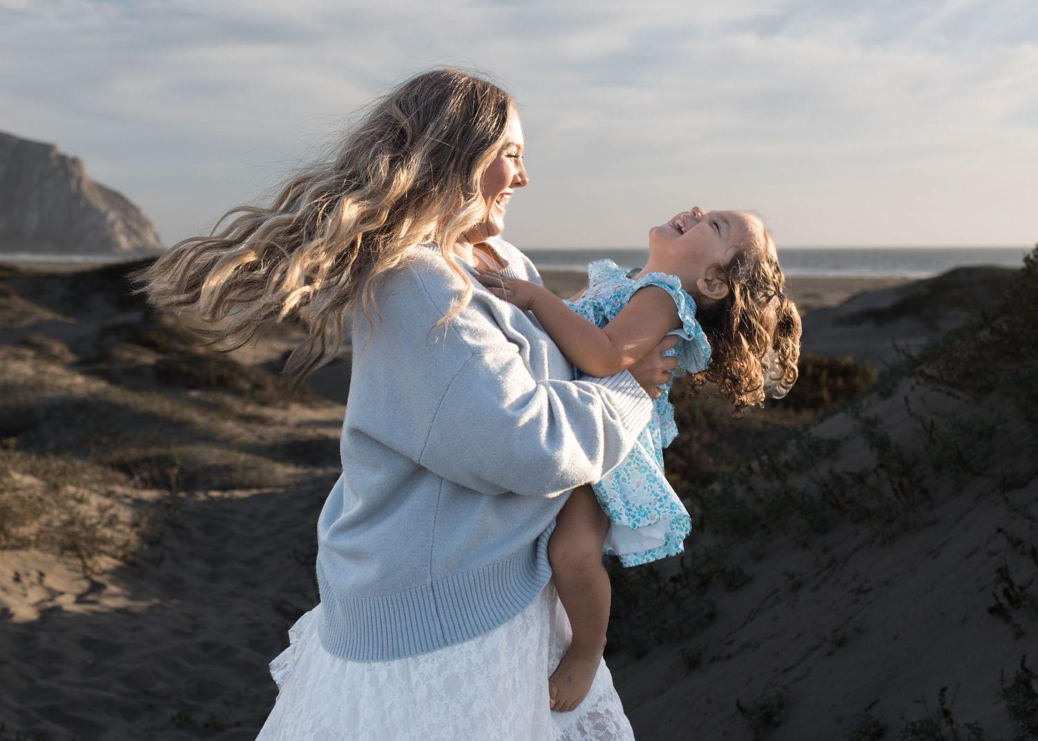 Mother and daughter embracing during a beautiful beach family photography session in California.