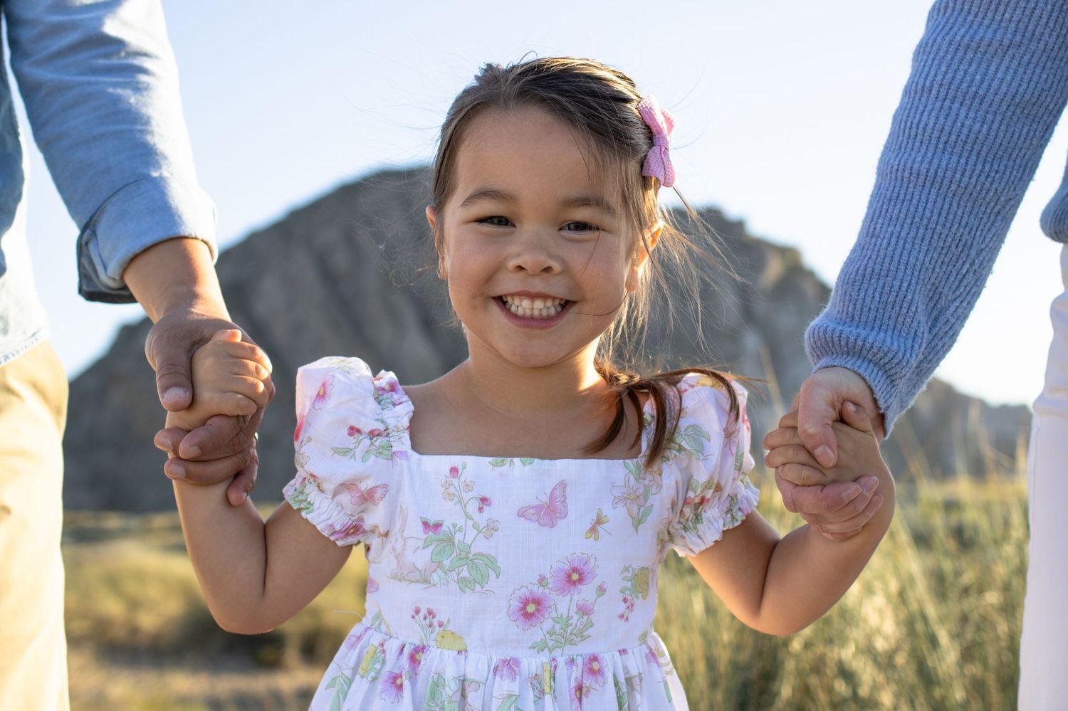 Little girl holding parents hands, candid family photography Central Coast