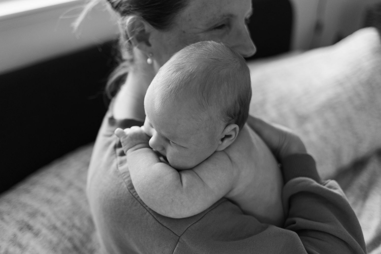 Mother cuddling her newborn baby during an intimate lifestyle newborn photography session in San Luis Obispo, California.