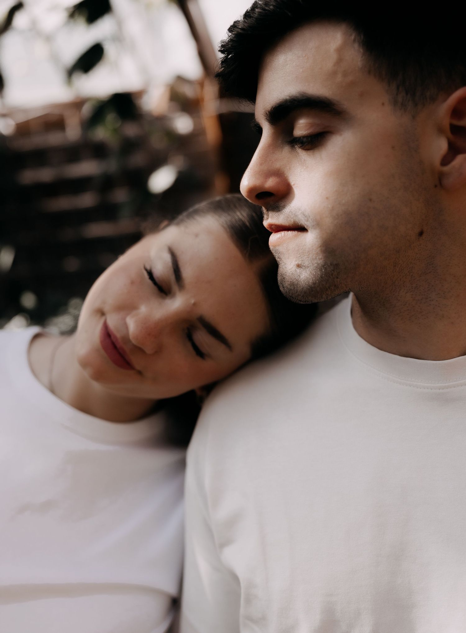 Intimate close-up of a couple with eyes closed, woman resting her head on mans shoulder.