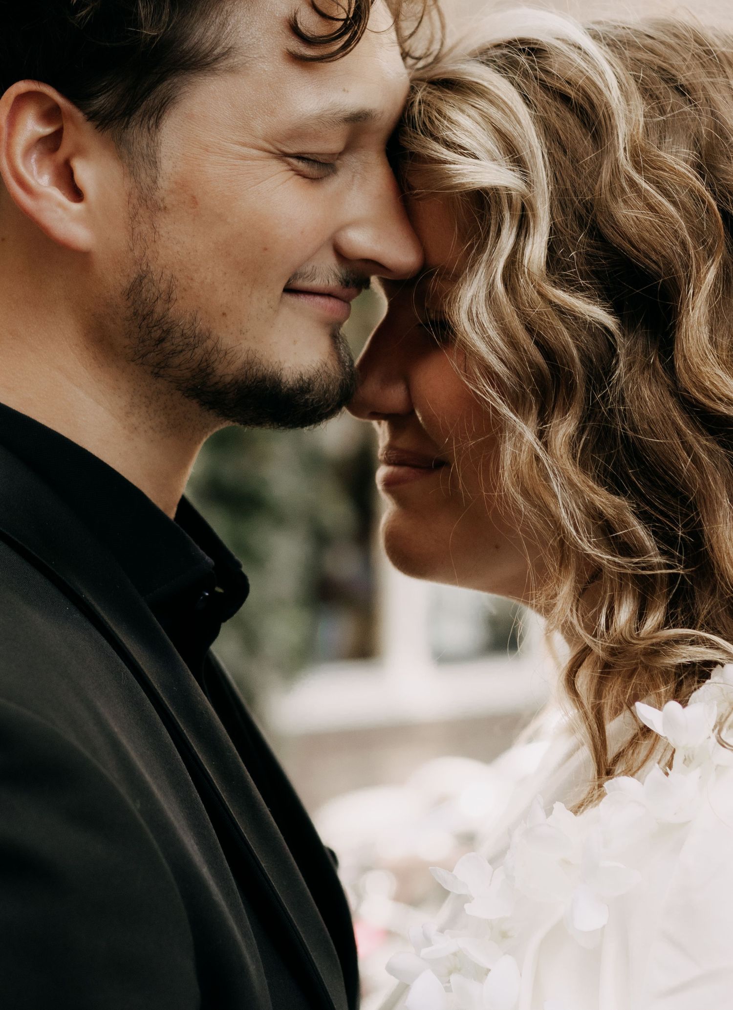 Intimate close-up of wedding couple touching foreheads tenderly, smiling softly together.