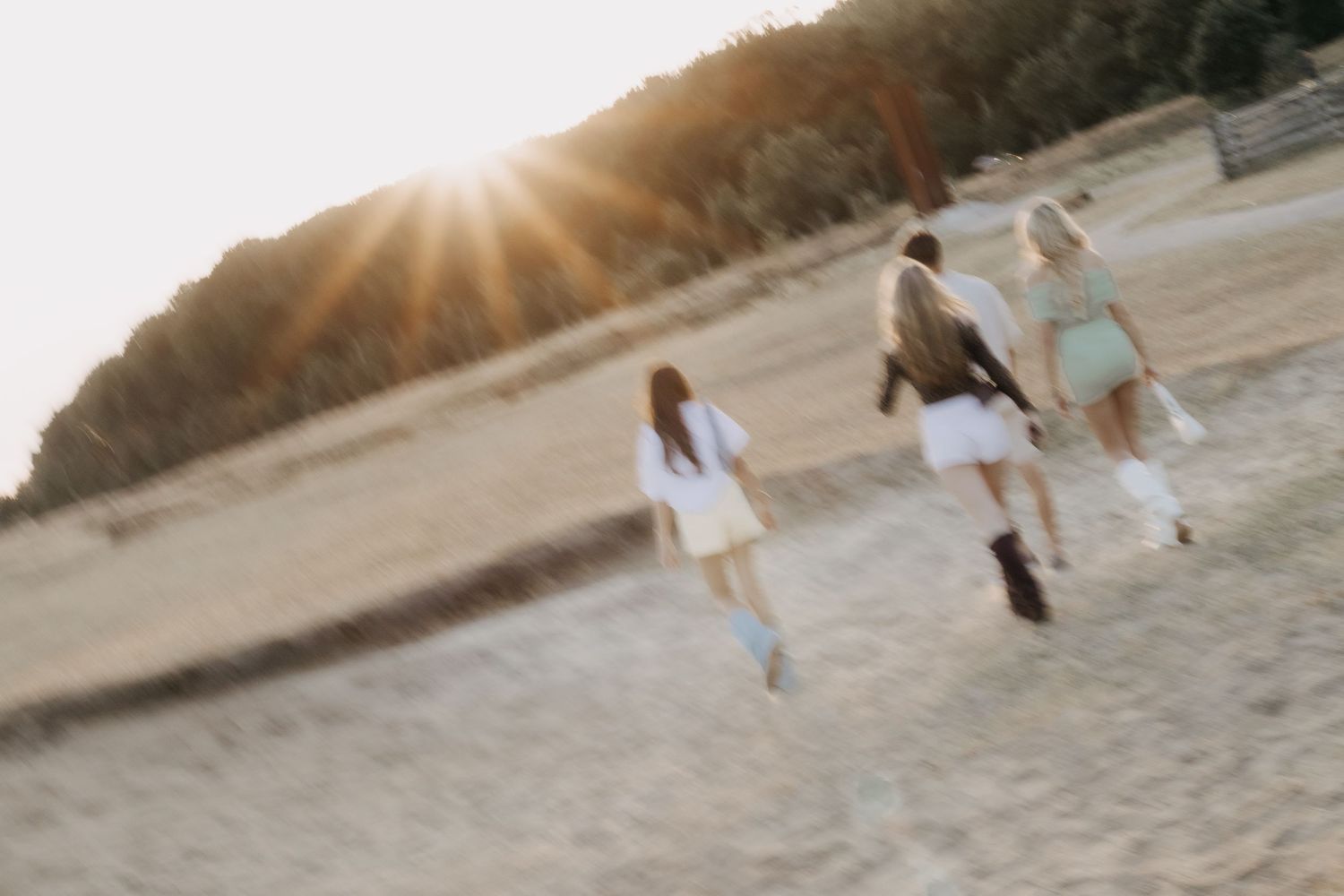 Group of friends walking on sandy beach at golden sunset hour.