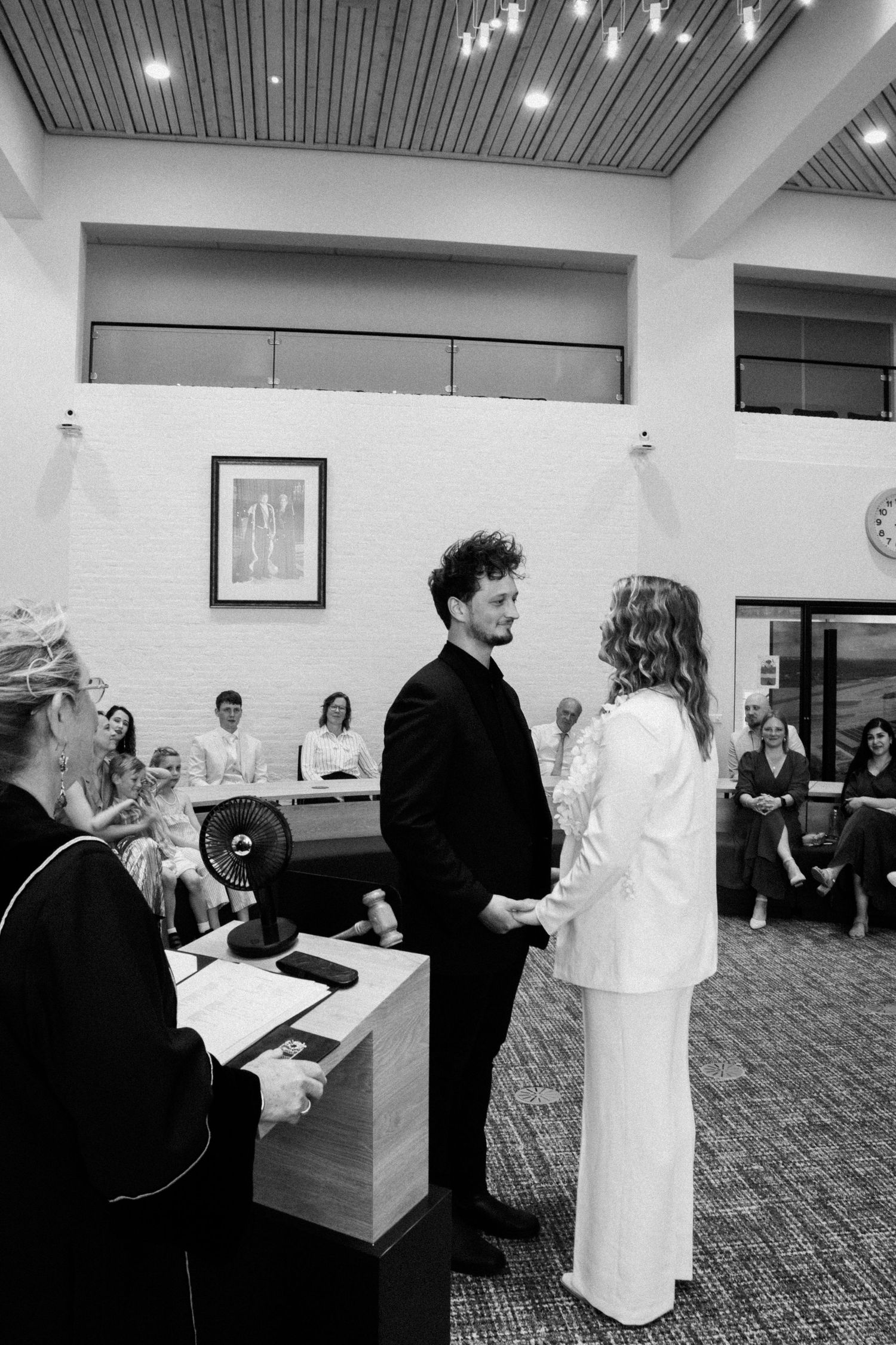Black and white photo of couple exchanging vows at a civil wedding ceremony indoors.