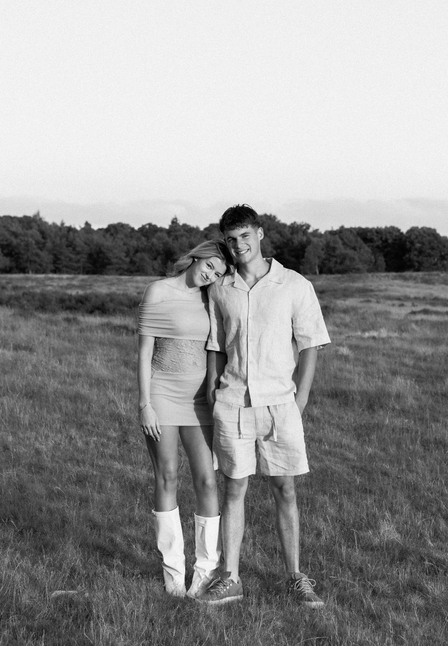 Black and white photo of a young couple posing together in an open field.