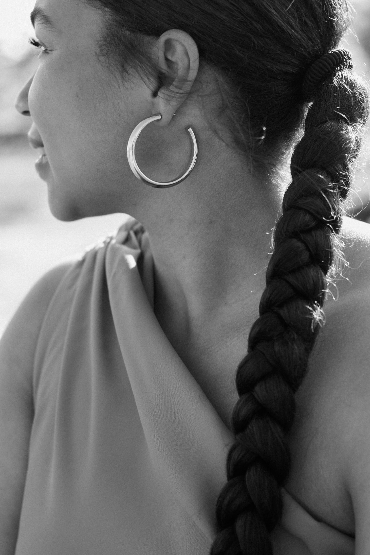 Black and white close-up of a woman with a braided ponytail wearing a large hoop earring.