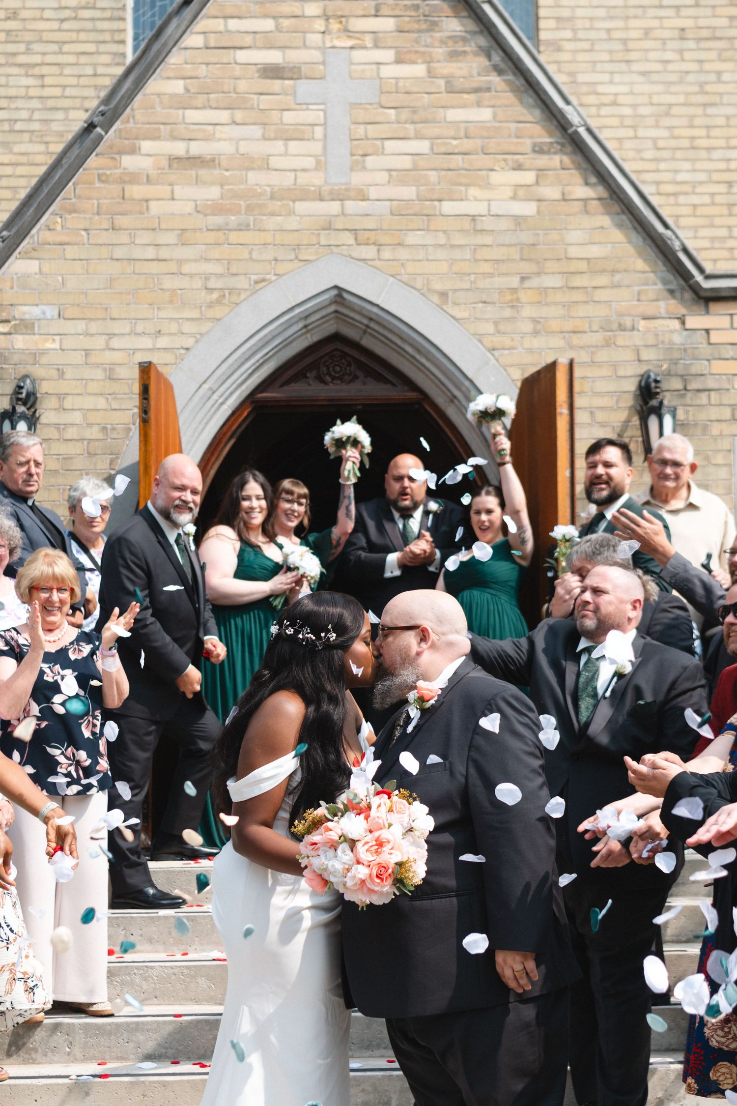 Bride and groom celebrate their wedding surrounded by family and friends outside of the church in Waterloo, Ontario.